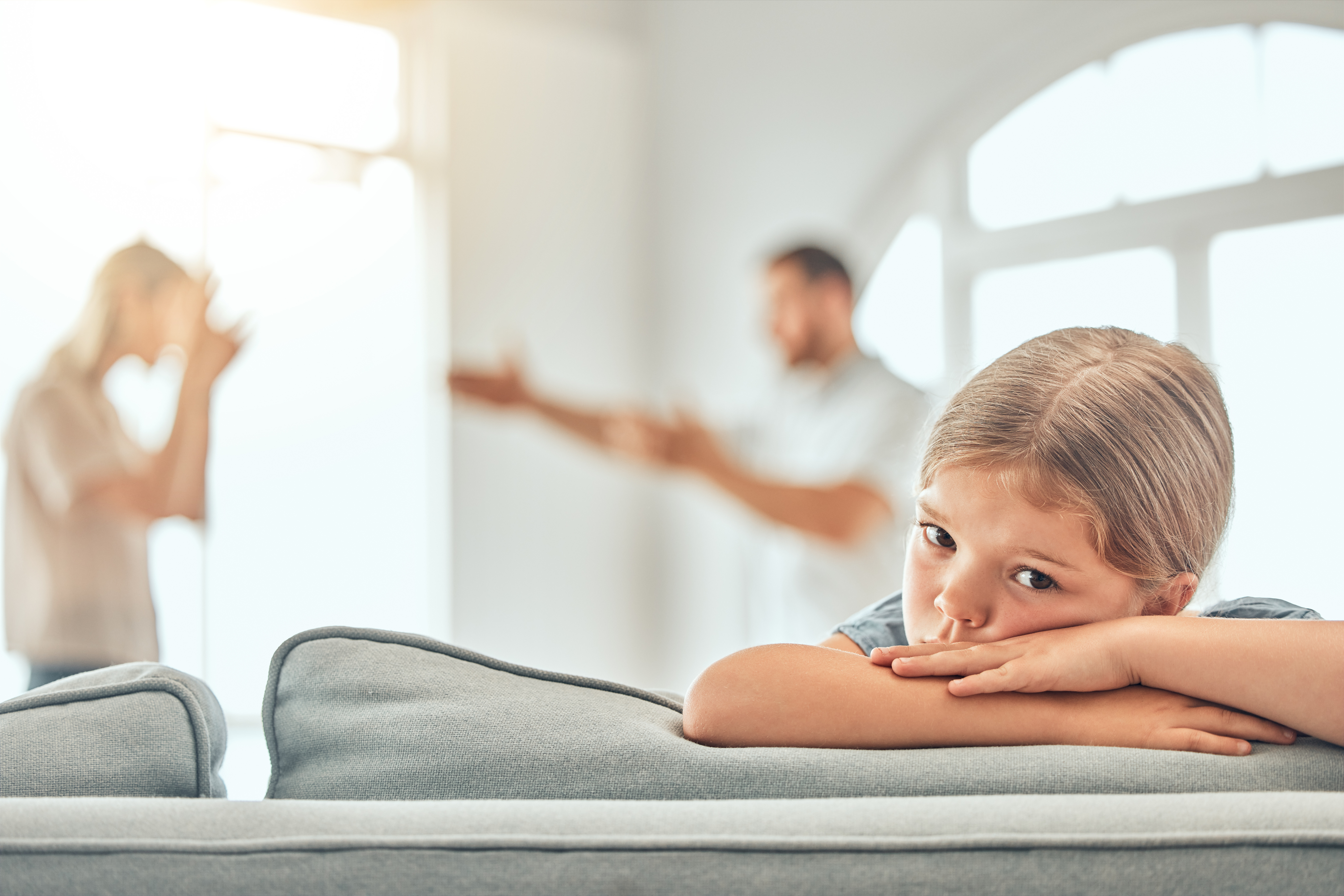 Divorce, sad and child on sofa with parents in argument for conflict, disagreement or fighting in living room. Young girl, angry man with woman for paternity test, distrust or wife with affair Child Support and Custody-Related Finances